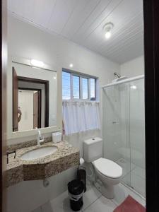 a bathroom with a toilet and a sink and a shower at Apartamento Orquídea in Porto Belo +1 photo