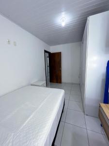 a bedroom with a white bed and a door at Apartamento Orquídea in Porto Belo