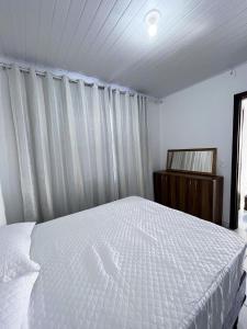 a bedroom with a white bed and a window at Apartamento Orquídea in Porto Belo