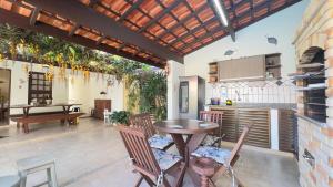 a kitchen and dining room with a table and chairs at Aconchego e diversão em Peruíbe sobrado com estrutura completa para sua família ar condicionado, churrasqueira ,academia, cervejeira, piscina in Peruíbe