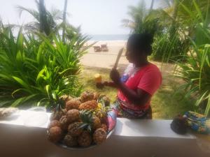 Una mujer de pie junto a una mesa con un plato de fruta. en Bungalow accés direct plage privée "Plage tropicale Chez Jack et Régine", en Grand-Bassam 21 fotos más