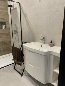 a white bathroom with a sink and a shower at ApartHouse in Klimontów