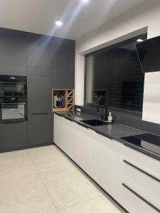 a kitchen with black and white cabinets and a sink at ApartHouse in Klimontów