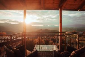 a view of the sun setting from a porch with a table at SkyView Dežno in Makole