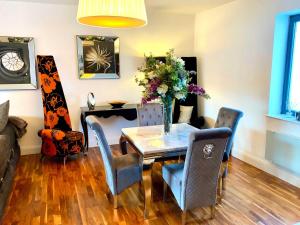 a dining room with a table and chairs with a vase of flowers at Regent View Apartment in Knutsford