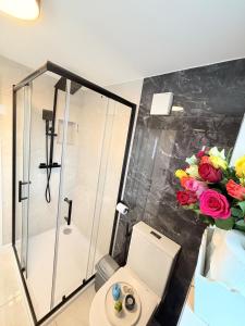 ein Bad mit einer Dusche, einem WC und Blumen in der Unterkunft Bright Modern Apartment in Northfield