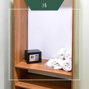 a book shelf with a clock and towels at Hotel Serenity in Tbilisi City