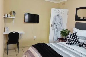 Un dormitorio con una cama con un vestido colgado en la pared. en Budget Stays at Olivia Pines Guesthouse, en Krugersdorp