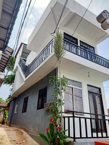 une maison blanche avec un balcon et une plante dans l'établissement Rian Rest, à Gangodawila