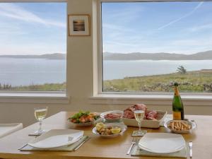 a table with food and wine and a large window at Taigh Na Beadan in Valtos