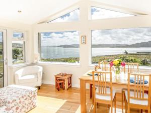 a dining room with a table and chairs and large windows at Taigh Na Beadan in Valtos