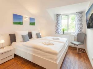 a white bedroom with a large bed and a chair at One-bedroom apartment in Sassnitz