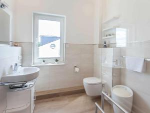 a white bathroom with a toilet and a sink at One-bedroom apartment in Sassnitz +12 photos