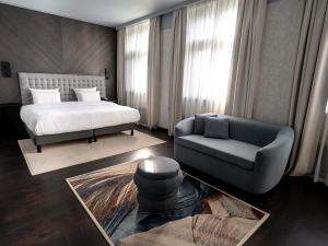 Un dormitorio con una cama, un sofá y una silla. en Pullman Riga Old Town - Renovated 2025, en Riga