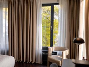 Una habitación de hotel con una cama, una silla y una ventana. en Pullman Riga Old Town - Renovated 2025, en Riga