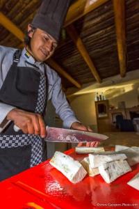 un homme préparant de la nourriture avec un grand couteau sur une table dans l'établissement Ortega'S Guest House, 