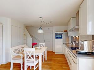 eine Küche mit weißen Schränken und einem Tisch und Stühlen in der Unterkunft Holiday apartment with 2 bedrooms in Oldsum + 5 Fotos