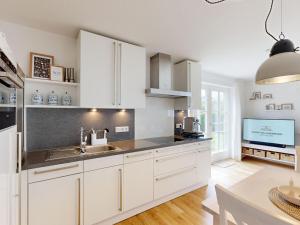 eine Küche mit weißen Schränken und einem Waschbecken und einem Tisch in der Unterkunft Holiday apartment with 2 bedrooms in Oldsum