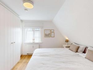 ein Schlafzimmer mit einem großen weißen Bett und einem Fenster in der Unterkunft Holiday apartment with 2 bedrooms in Oldsum