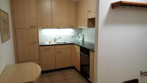 a small kitchen with wooden cabinets and a sink at Alpen-Fewo, Residenza Quadra 25 in Flims +5 photos
