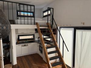 a loft bed in a tiny house with a kitchen at Tiny House zum Wohlfühlen in Scheidegg