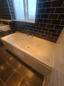 een badkamer met een bad en een blauwe tegelmuur bij Coastal town properties in Jarrow