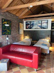 a red leather couch in a room with two beds at 't ouw ateljeeke in Budel
