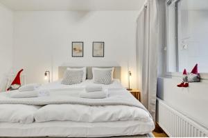 a white bedroom with a large white bed with red decorations at Adorable Arctic Apartments - Private Sauna & Free Parking in Rovaniemi