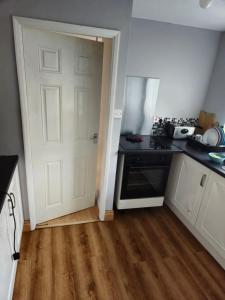 Una cocina con una estufa negra y una puerta blanca. en Constable Road, en Moffat