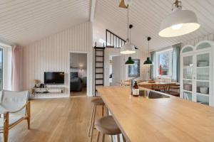 a kitchen and living room with a large wooden table at Snug In Snogebæk A Modern Cozy Summer House in Neksø