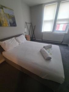 een groot wit bed met twee handdoeken erop bij Coastal town properties in Jarrow