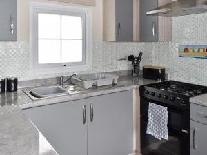 una cocina con fregadero y estufa en Sunnyside Lodge, en Sandown