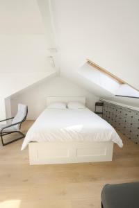 a white bedroom with a bed and a chair at Spacious house with garden, 15 minutes from Paris in Houilles