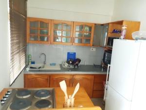 a kitchen with wooden cabinets and a white refrigerator at Beachfront apartment-perfect sea escape! in Flic-en-Flac +12 photos