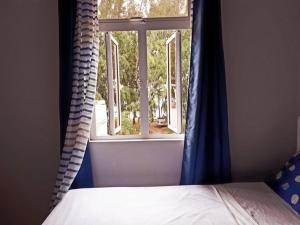 a bedroom with a bed and a window with blue curtains at Beachfront apartment-perfect sea escape! in Flic-en-Flac