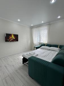 a bedroom with a bed and a tv on the wall at ЖК Арман кала 1- комнатная квартира in Zhezdi