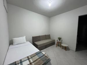 een witte kamer met een bed en een bank bij Recanto Canuto D in Diamantina