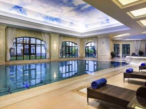 a large swimming pool in a building with a large ceiling at Pullman Tangshan in Tangshan