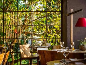 a restaurant with tables and chairs and a large window at Santa Teresa Hotel Rio de Janeiro - MGallery Collection in Rio de Janeiro