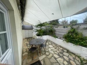 a patio with a table and chairs and an umbrella at Les Dunes de Longchamp in Saint-Lunaire