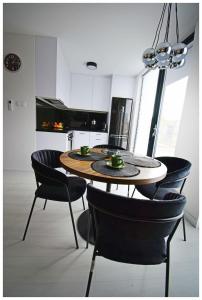 a dining room table with black chairs and a kitchen at Biała chatka w Krzaczastym Zakątku 