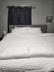 een groot wit bed met witte lakens en kussens bij Entire Spacious House in New Jersey in East Orange