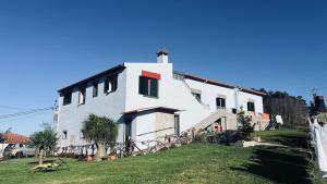 a large white house with a grass yard at Villa do Monte Sunset in Porto Moniz