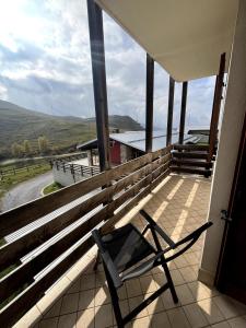 a chair on a porch with a view of the water at Holiday PratoNevoso - Sci ai piedi in Prato Nevoso
