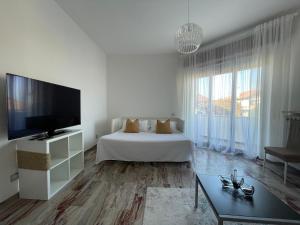 een witte kamer met een bed en een flatscreen-tv bij Casa Vacanze Ilenia in Marina di Montemarciano