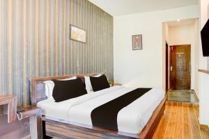 a bedroom with a large bed with black and white pillows at Hotel O Raj Ambessy in Rāmpura