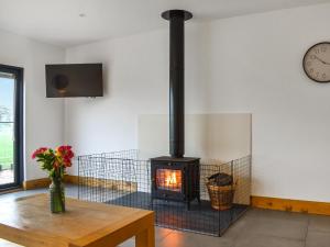 a fireplace in a room with a table and a clock at Acre Luxury Lodges-Cedar Lodge in Evenjobb