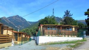 a row of wooden buildings with mountains in the background at Top Village in Cogoleto