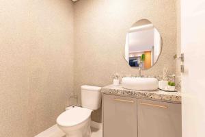 a bathroom with a toilet and a sink and a mirror at Apartamento Lindíssimo na Praia de Bombas in Bombas +15 photos