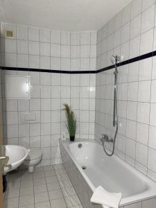 a white tiled bathroom with a tub and a toilet at Anger17, Zentrales 2-Zimmer-Apartment in Dessau in Dessau